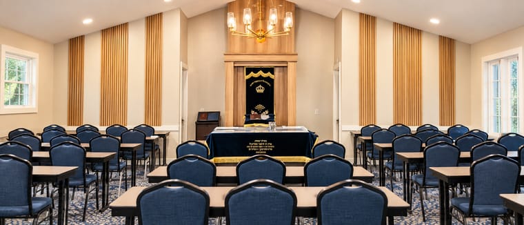 The main sanctuary set with tables and blue chairs facing the aron
